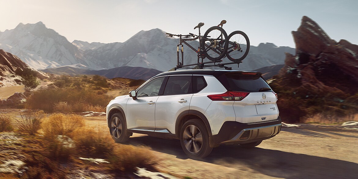 2022 Nissan Rogue illustrating off-road capability in the mountains with bikes on roof rack. 