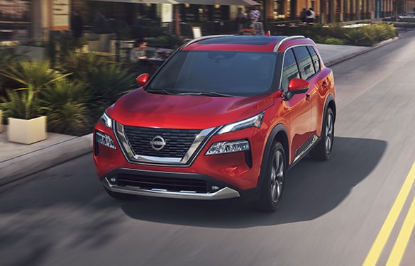 2022 Nissan Rogue in Scarlet Ember driving on a city street illustrating gas mileage.