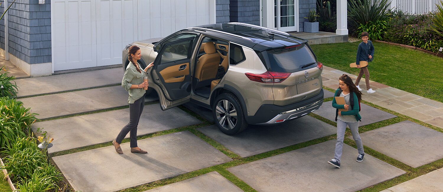 2022 Nissan Rogue in a driveway with door open and family about to get in.