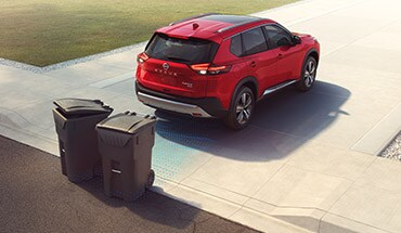 2022 Nissan Rogue showing car backing up and avoiding trash cans with rear sonar. 