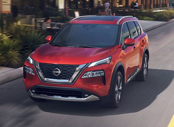 2023 Nissan Rogue in Scarlet Ember driving on a city street illustrating gas mileage.