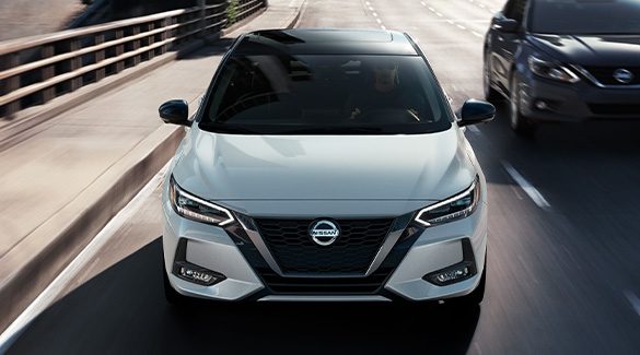 2023 Nissan Sentra front view in white driving through city streets.