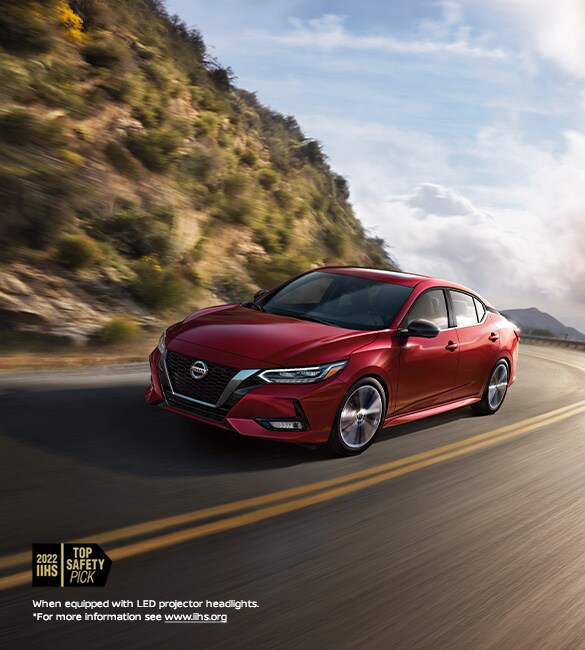2023 Nissan Sentra in Scarlet Ember Tintcoat driving swiftly in the mountains.